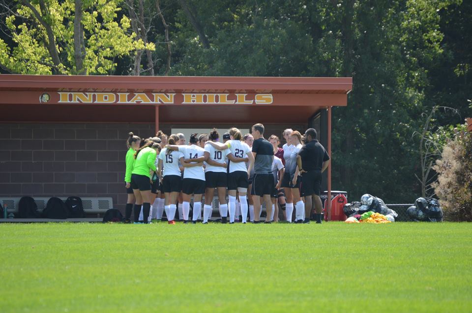 Women's Soccer Team huddled together strategising before the game.
